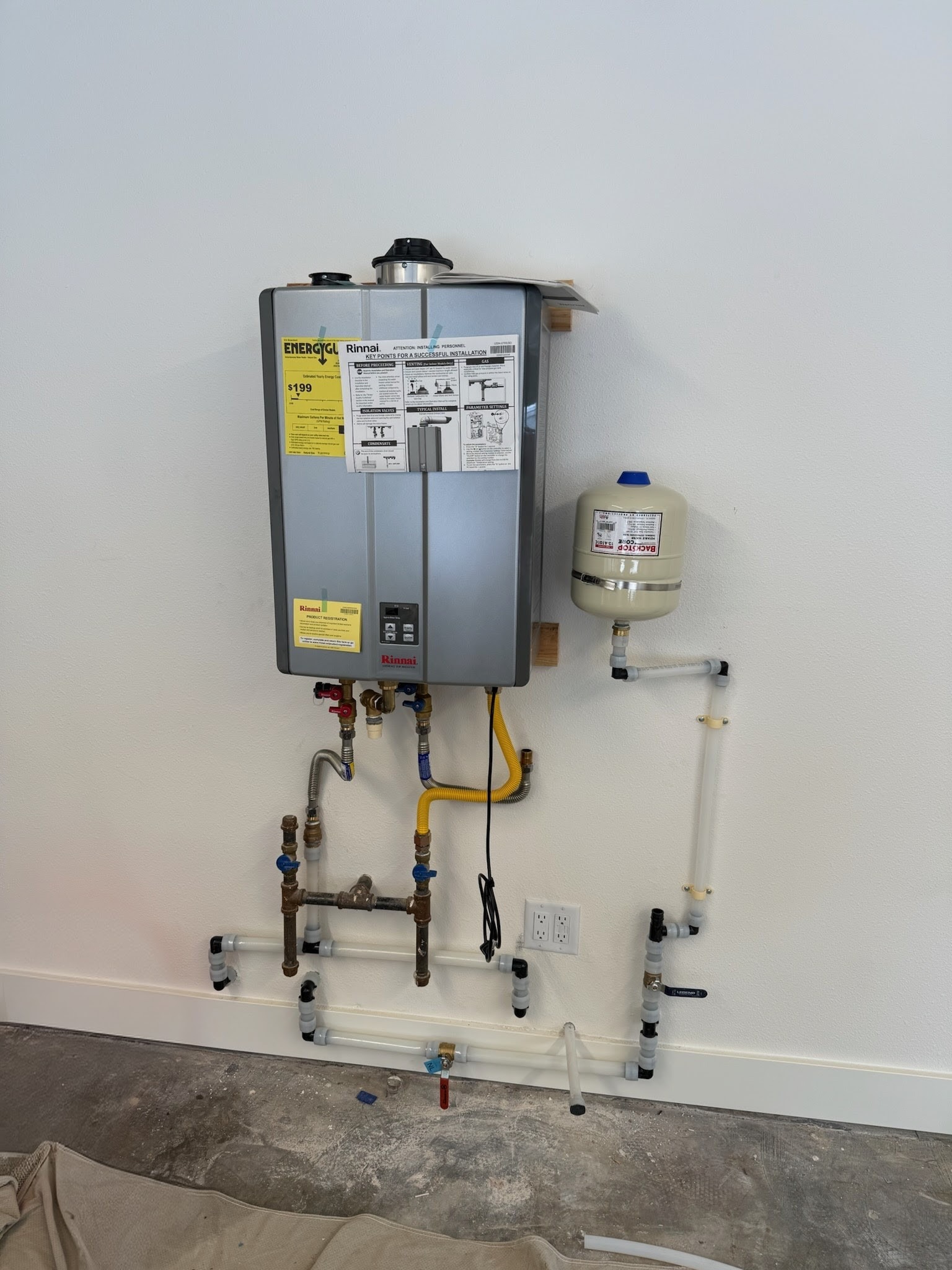 Rinnai tankless gas water heater with expansion tank and exposed plumbing